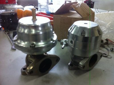 Normal wastegate on left, mini watercooled wastegate on right. Both are 38mm (the normal one is there for a size comparison). You can see the mini one is made up of three alloy pieces in the top section. The top hat to keep the spring down, the bottom cradle for the spring to mount on and the lower ring which is the water cooling ring to keep heat out of the diaphragm (We've had problems before with diaphragms heating up and getting holes, even expensive turbosmart ones).